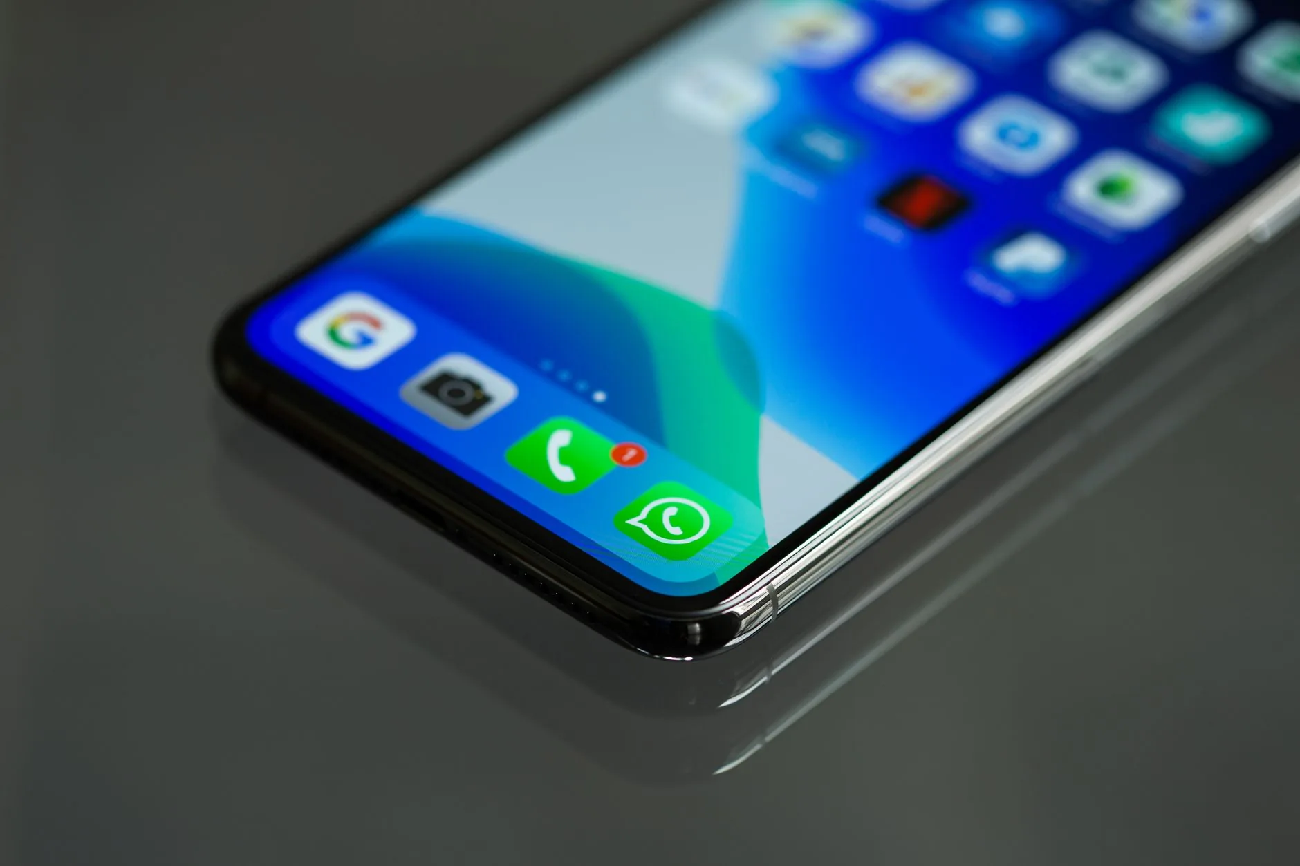 Celular exibindo conversas de atendimento no WhatsApp Business sobre uma mesa de trabalho