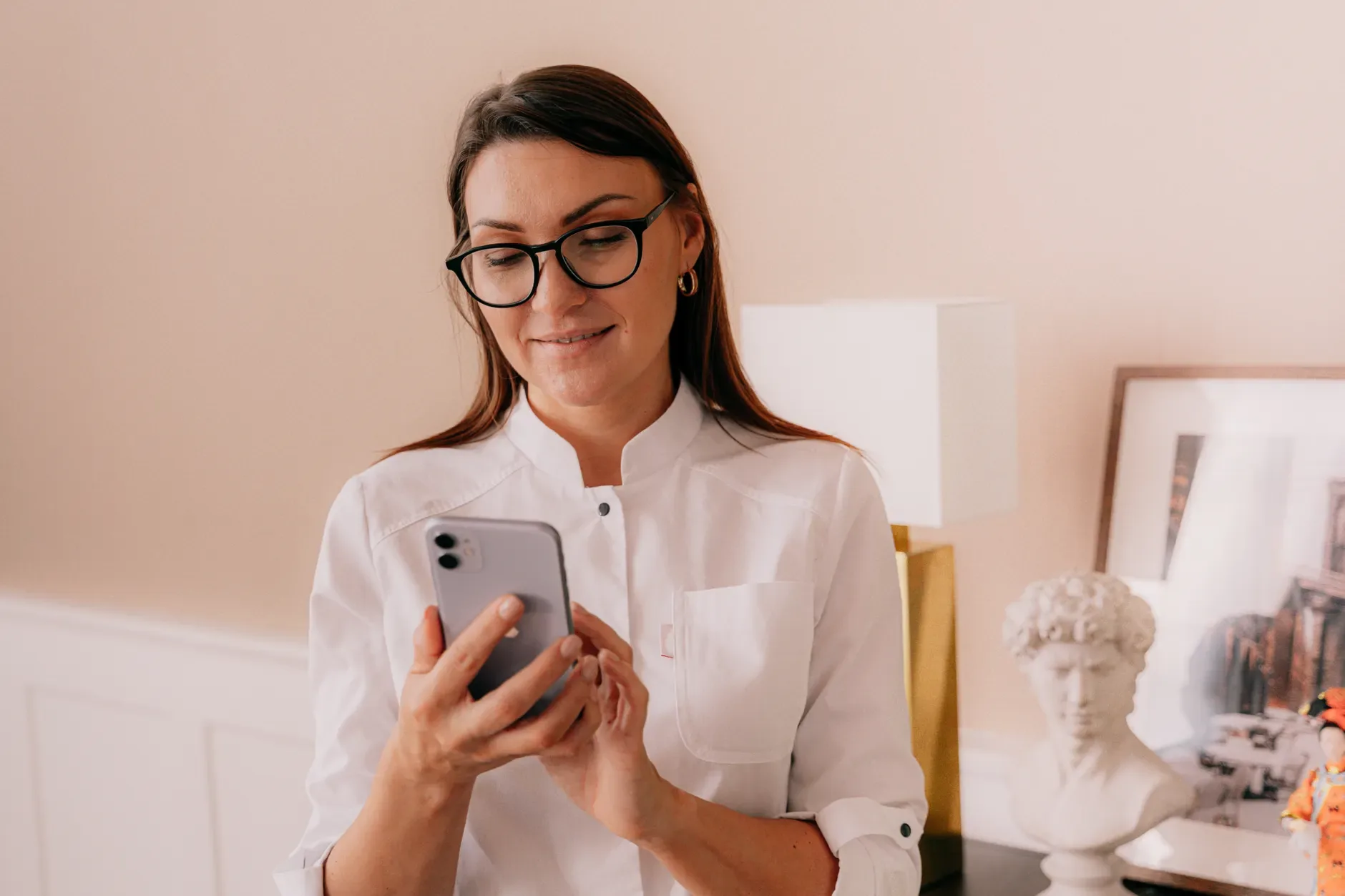 Recepcionista de clínica digitando mensagem de WhatsApp no celular para chamar paciente de retorno