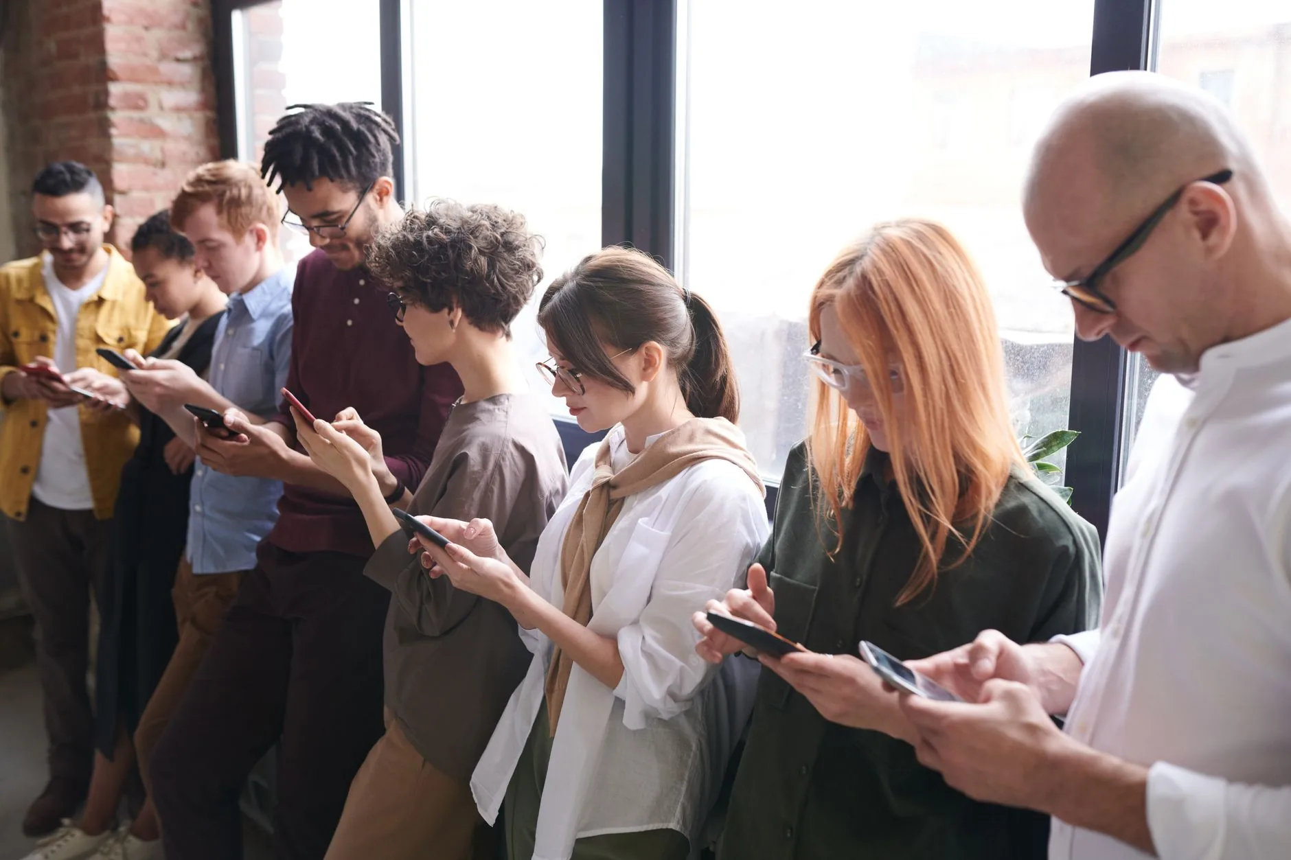 Equipe de atendimento em um escritório, cada pessoa acompanhando conversas de clientes no celular durante um turno