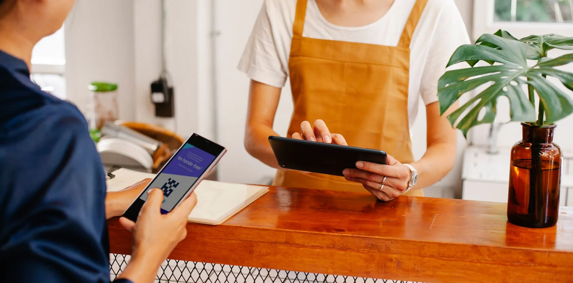 Celular sobre balcão de loja exibindo conversa de atendimento no WhatsApp Business