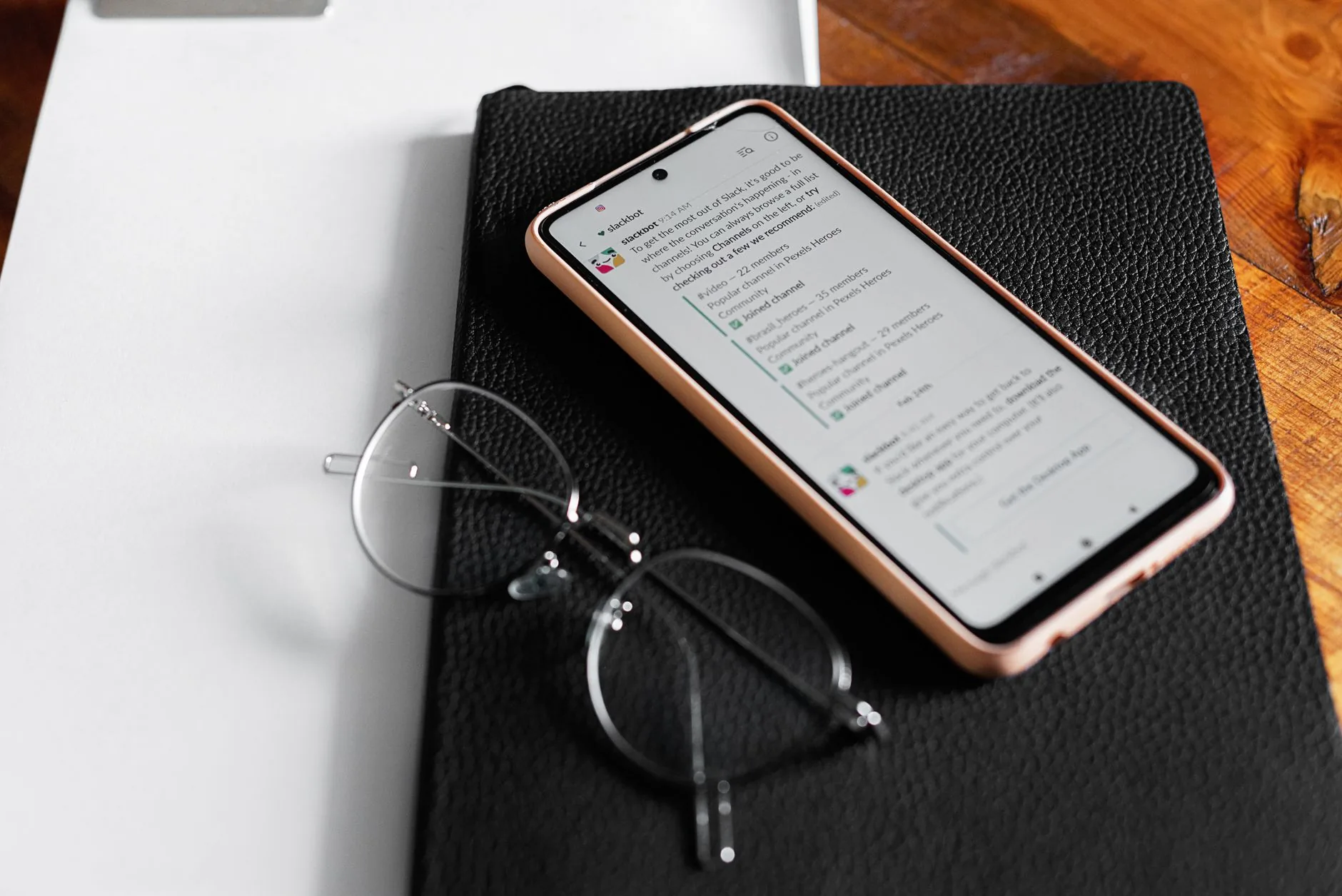Celular exibindo conversas de atendimento no WhatsApp Business sobre uma mesa de escritório